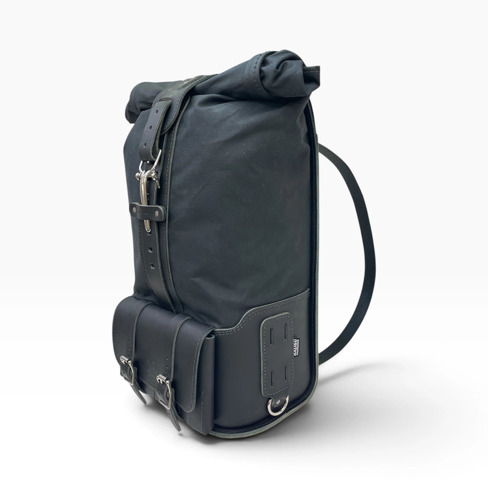A black roll-top backpack with leather straps, buckles, and a shoulder strap, photographed on a clean white background.